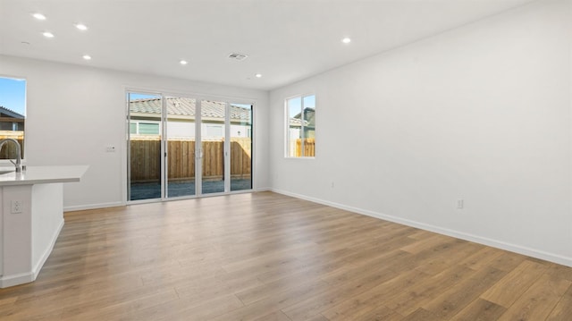 unfurnished living room with sink and light hardwood / wood-style flooring