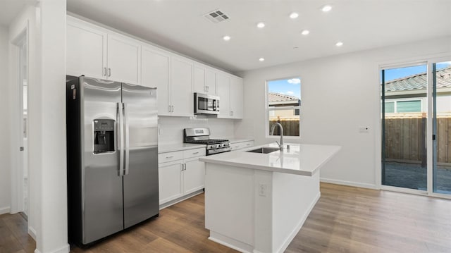 kitchen featuring sink, appliances with stainless steel finishes, a kitchen island with sink, a healthy amount of sunlight, and white cabinets