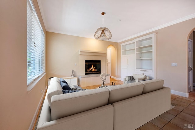 tiled living room featuring built in shelves, crown molding, and a fireplace