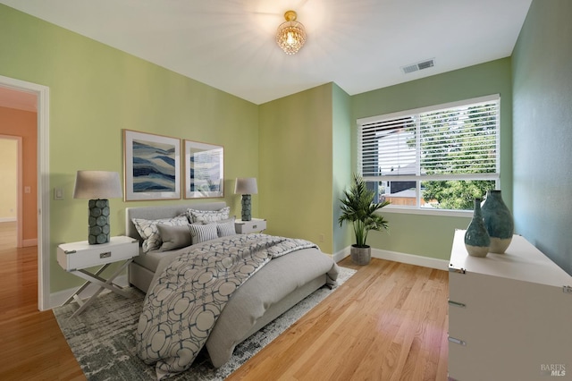 bedroom with baseboards, visible vents, and wood finished floors