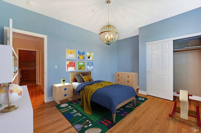 bedroom with a closet, baseboards, wood finished floors, and a chandelier