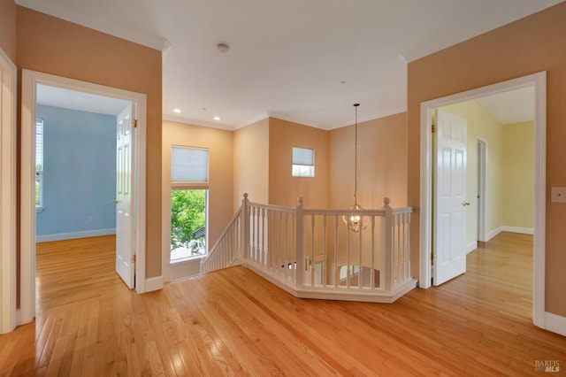 hallway featuring an upstairs landing, crown molding, baseboards, wood finished floors, and an inviting chandelier