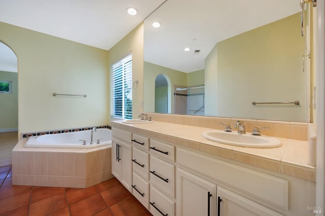 full bathroom featuring tile patterned flooring, a sink, double vanity, and a garden tub