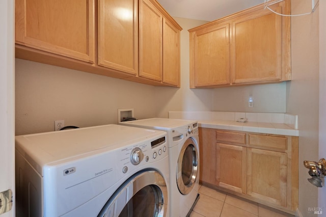 laundry area featuring washing machine and clothes dryer, cabinet space, and light tile patterned floors
