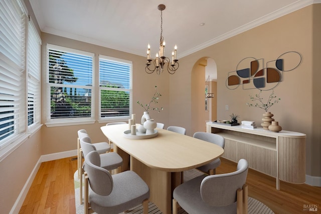 dining area with arched walkways, crown molding, baseboards, and light wood-type flooring