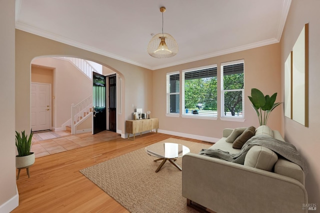 living area with stairs, crown molding, light wood finished floors, baseboards, and arched walkways