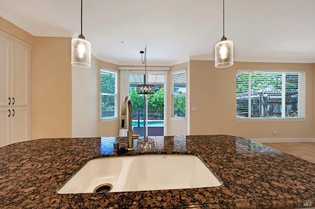 room details featuring crown molding, white cabinets, dark stone countertops, and a sink