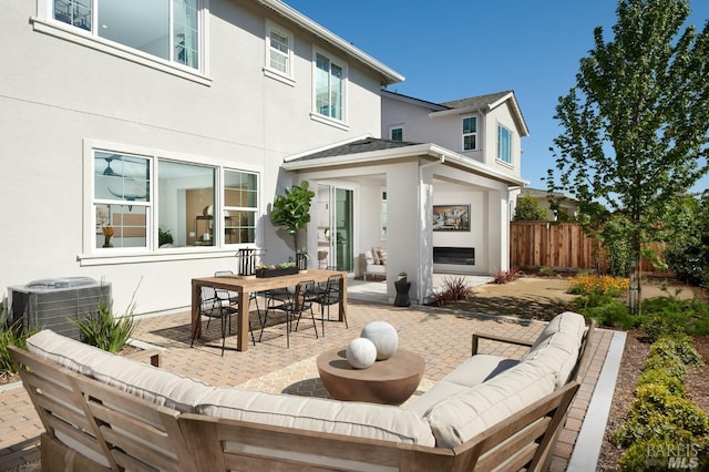 back of property with central AC unit, a patio area, and an outdoor hangout area