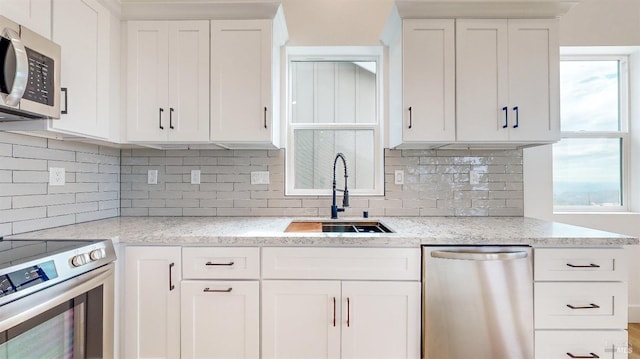 kitchen featuring white cabinetry, appliances with stainless steel finishes, light stone countertops, and sink