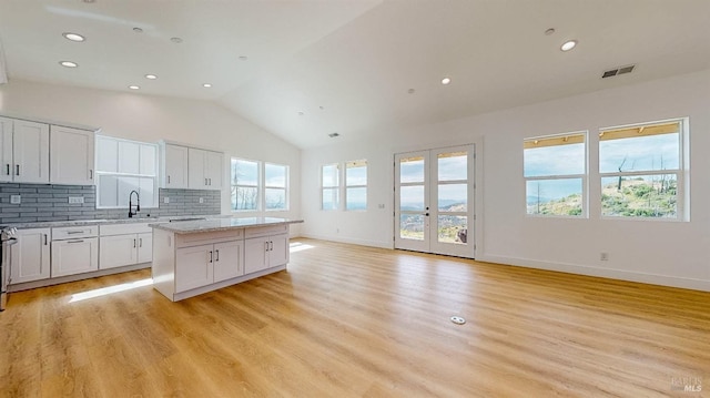 kitchen featuring white cabinetry, light stone countertops, a kitchen island, and light hardwood / wood-style flooring