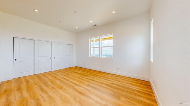 unfurnished bedroom featuring two closets and light hardwood / wood-style floors