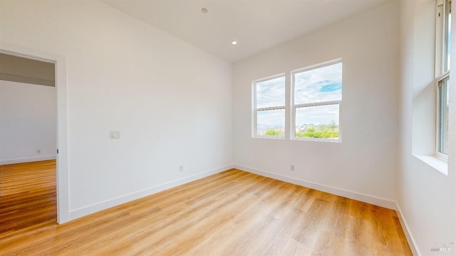 empty room with vaulted ceiling and light hardwood / wood-style floors