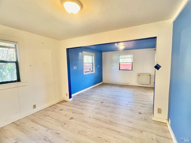 spare room featuring a wealth of natural light, light wood-style flooring, and baseboards