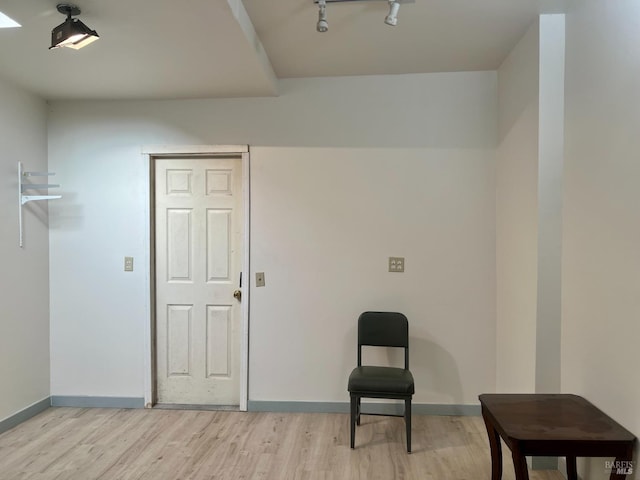 living area with track lighting, light wood-type flooring, and baseboards