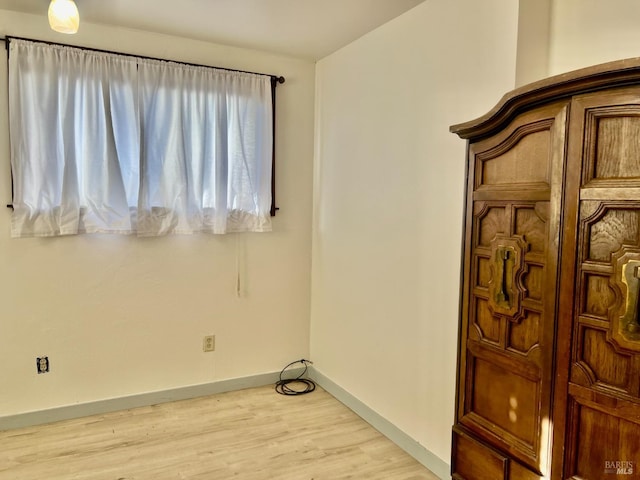 spare room with baseboards and light wood finished floors