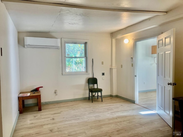 interior space with baseboards, a wall mounted air conditioner, and light wood-style floors