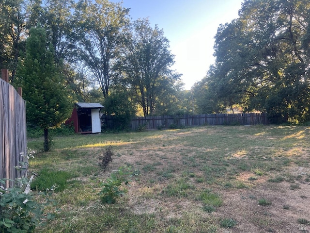 view of yard with a storage shed, fence, and an outbuilding