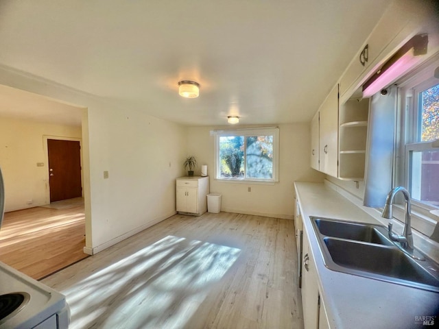 kitchen with white cabinets, light countertops, light wood-style floors, open shelves, and a sink