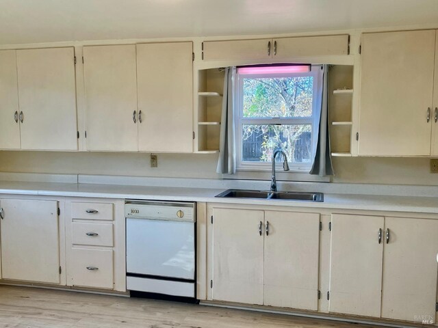 kitchen featuring light wood finished floors, open shelves, light countertops, white dishwasher, and a sink