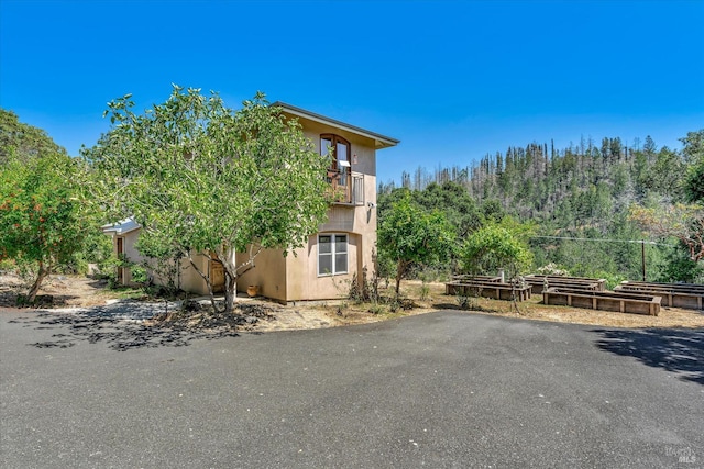 view of side of property with a balcony, a garden, and stucco siding