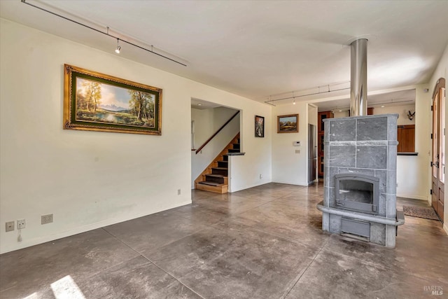 unfurnished living room with rail lighting, concrete floors, and stairway