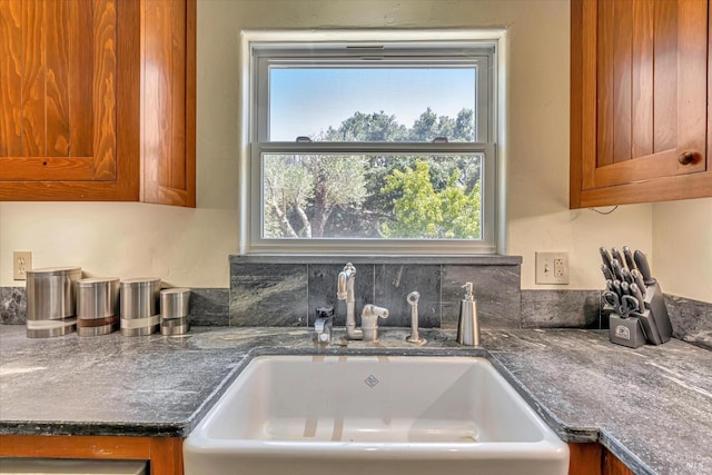 kitchen with brown cabinetry, dark countertops, and a sink