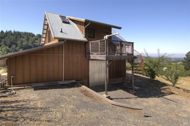 view of side of home featuring board and batten siding, metal roof, a wooden deck, and stairs