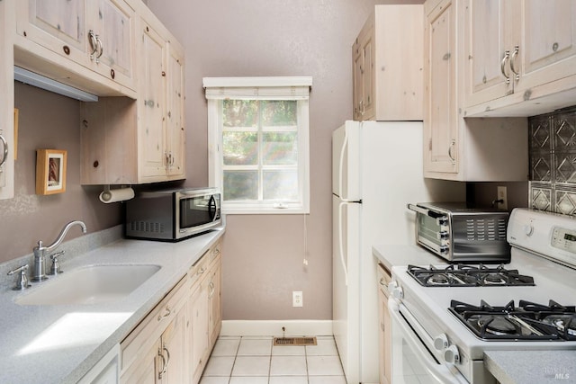 kitchen featuring white gas stove, light tile patterned floors, and sink