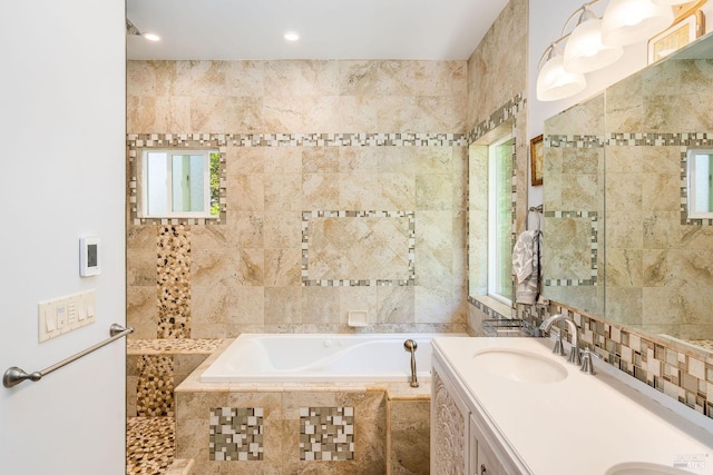 bathroom with vanity, a relaxing tiled tub, and tile walls