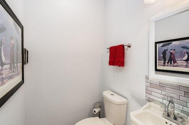 bathroom featuring backsplash, sink, and toilet