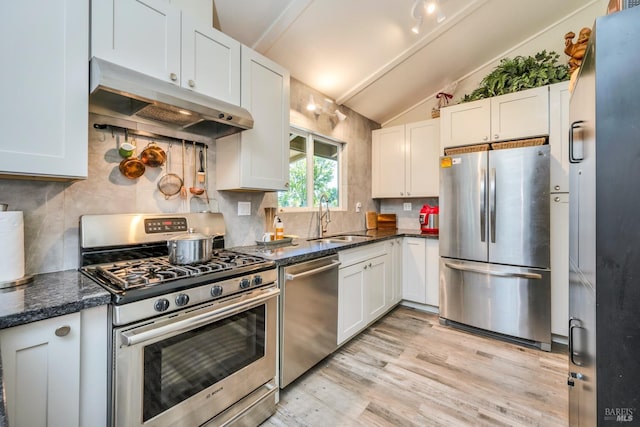 kitchen featuring appliances with stainless steel finishes, white cabinetry, lofted ceiling, and sink