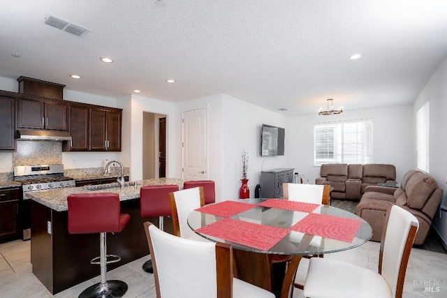 dining area with light tile patterned flooring, a textured ceiling, a chandelier, and sink