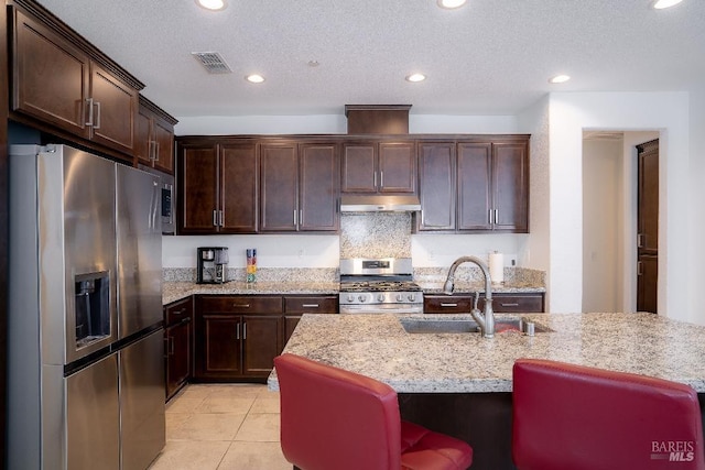 kitchen featuring sink, appliances with stainless steel finishes, light stone counters, and a textured ceiling