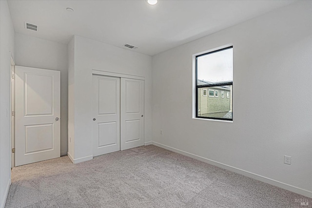 unfurnished bedroom with light carpet and a closet