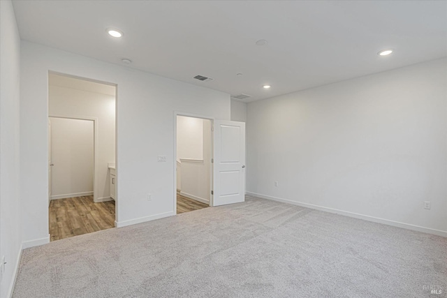 unfurnished bedroom with connected bathroom, a spacious closet, a closet, and light colored carpet