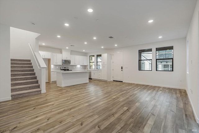 unfurnished living room featuring a healthy amount of sunlight and light hardwood / wood-style floors