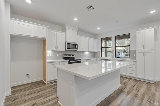 kitchen featuring light wood-type flooring, stainless steel appliances, and white cabinetry