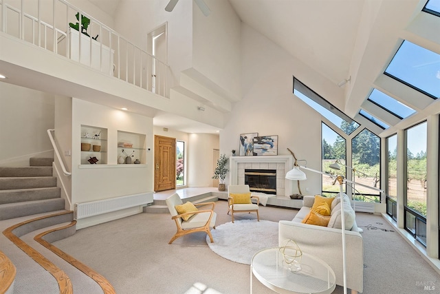 carpeted living room with a tile fireplace, built in shelves, and high vaulted ceiling