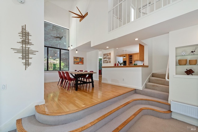 dining space featuring hardwood / wood-style floors, a high ceiling, and radiator heating unit