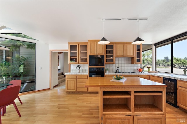 12430 Fiori Ln, Sebastopol, CA 95472 - kitchen featuring black appliances, beverage cooler, decorative backsplash, decorative light fixtures, and light wood-type flooring