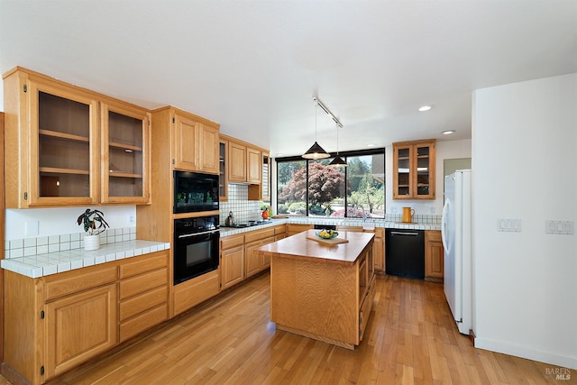 kitchen featuring black appliances, a center island, light wood-type flooring, and rail lighting