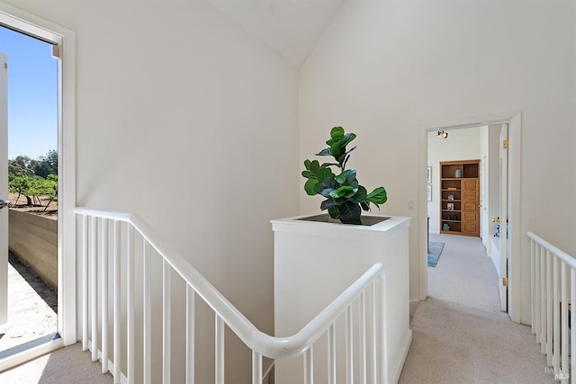 hall with light colored carpet and vaulted ceiling