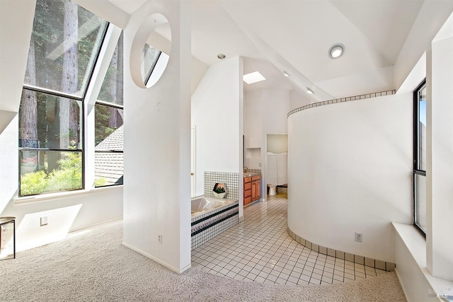 bathroom with tile patterned flooring, lofted ceiling, and tiled tub