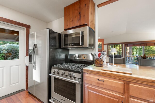 21995 Ansel Ct, Timber Cove, CA 95450 - kitchen featuring stainless steel appliances, lofted ceiling, light wood-style flooring, butcher block countertops, and brown cabinetry