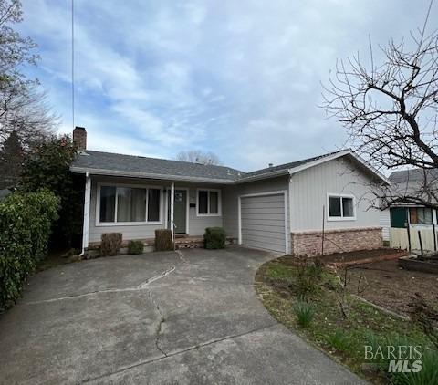 single story home featuring an attached garage, a chimney, and concrete driveway