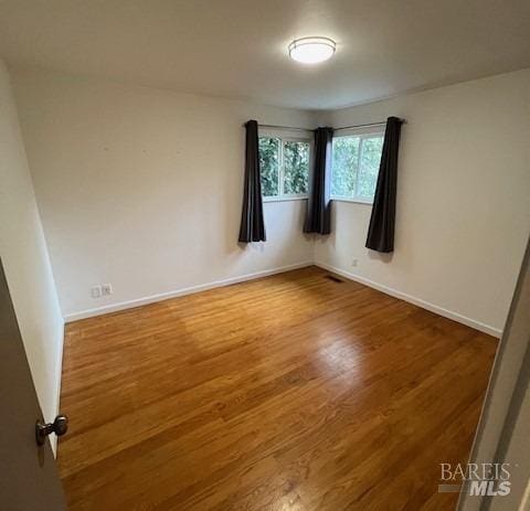 empty room featuring wood finished floors and baseboards