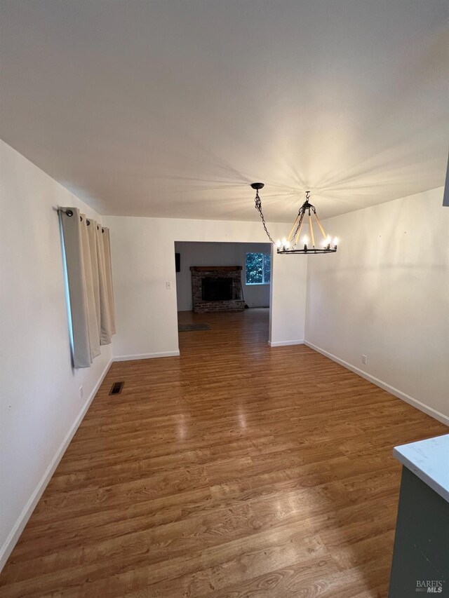 unfurnished living room featuring a fireplace, a chandelier, and hardwood / wood-style floors