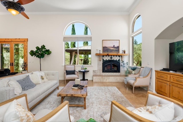 living room featuring crown molding, baseboards, a tiled fireplace, and light tile patterned flooring