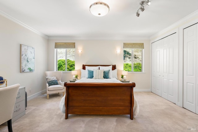 bedroom with ornamental molding, light carpet, baseboards, and multiple closets