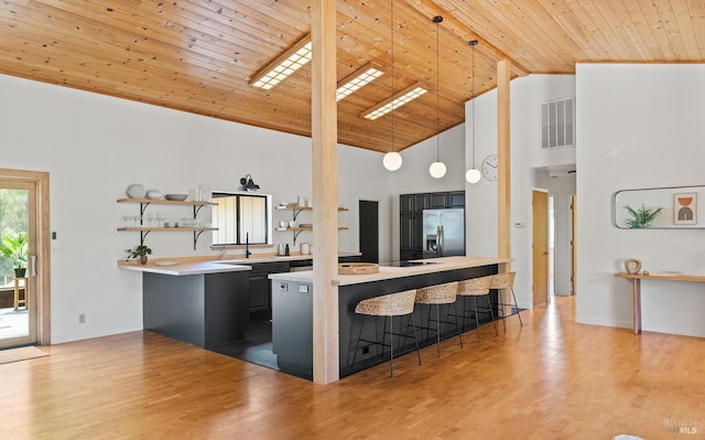 kitchen featuring stainless steel fridge with ice dispenser, light wood-type flooring, light countertops, wooden ceiling, and a kitchen breakfast bar